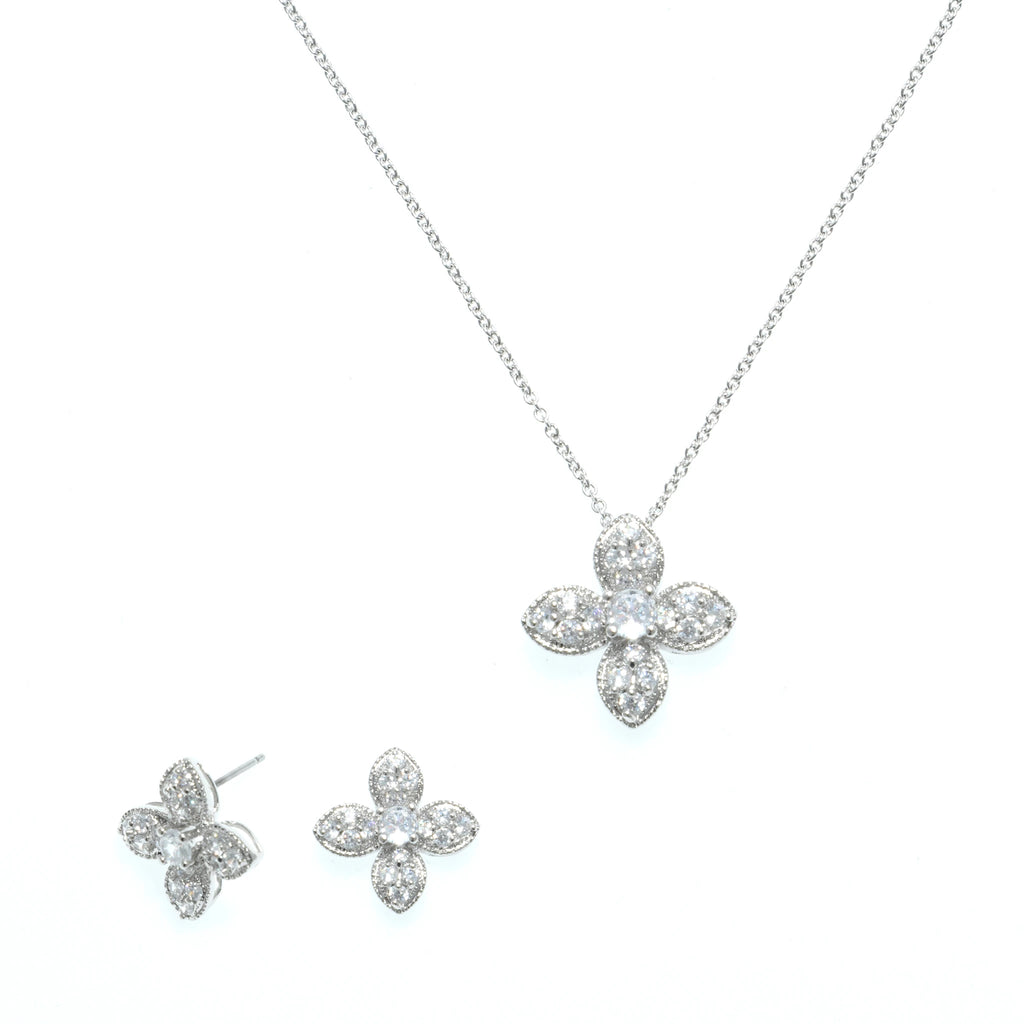 طقم مجوهرات الزهر الرباعي الناعم  مع ترصيع مكثف بأحجار الزركون البيضاء الشفافة Delicate four-petal floral jewelry set, richly studded with clear white zircon stones.