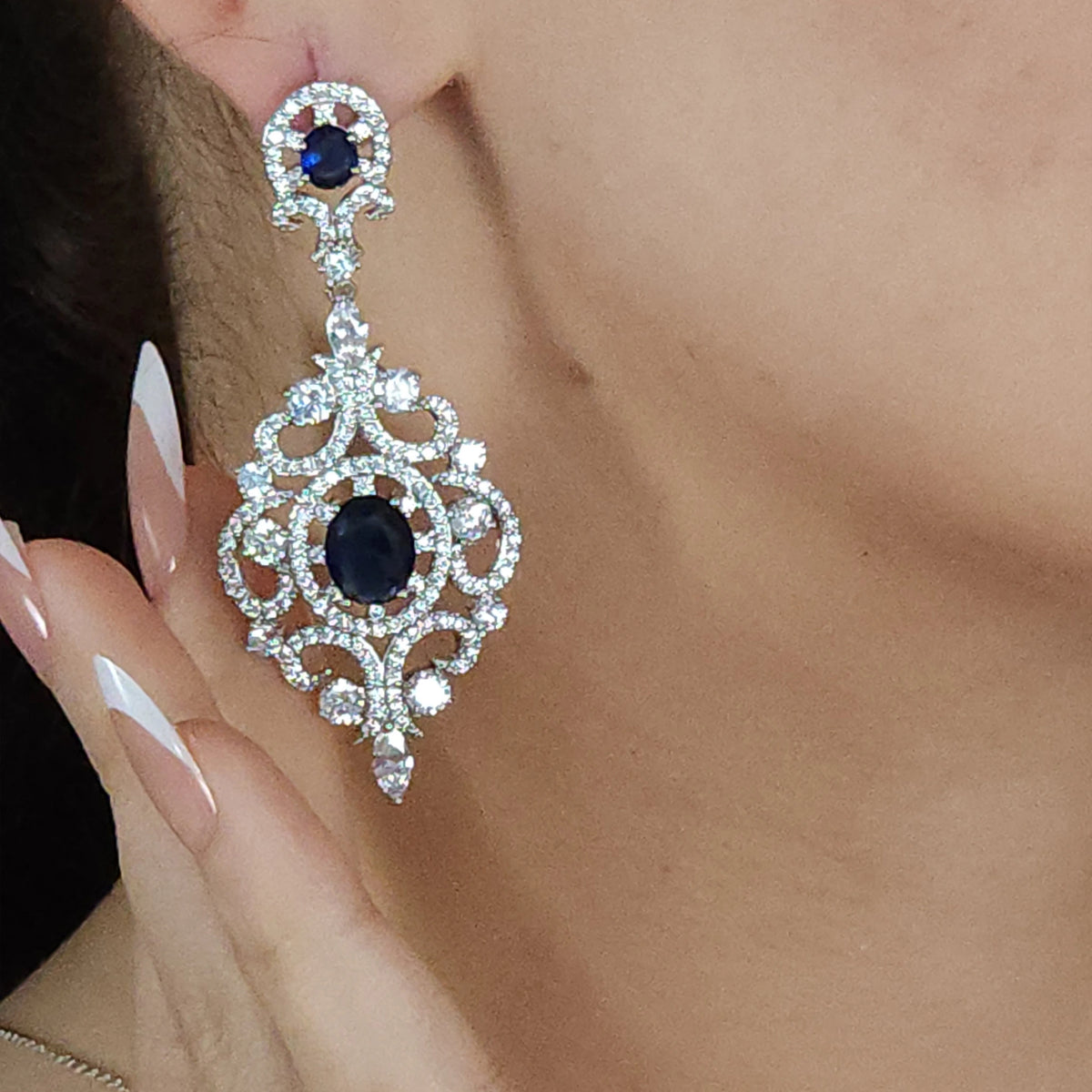 طقم مرصع بأحجار الزركون الشفافة، مع أحجار أزرق ملكية ذات اللون الكحلي العميق Jewelry set adorned with clear zircon stones and deep navy-blue royal blue stones.